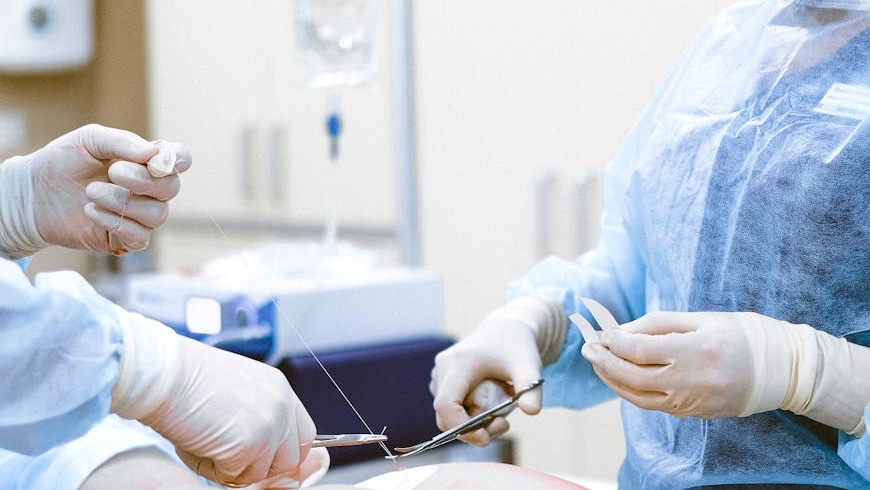 Two surgeons operating on a patient showing how to fix uneven breast implants