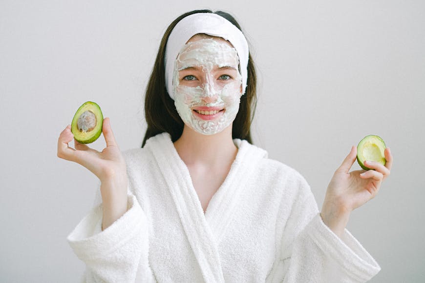 A woman with a face mask holding an avocado