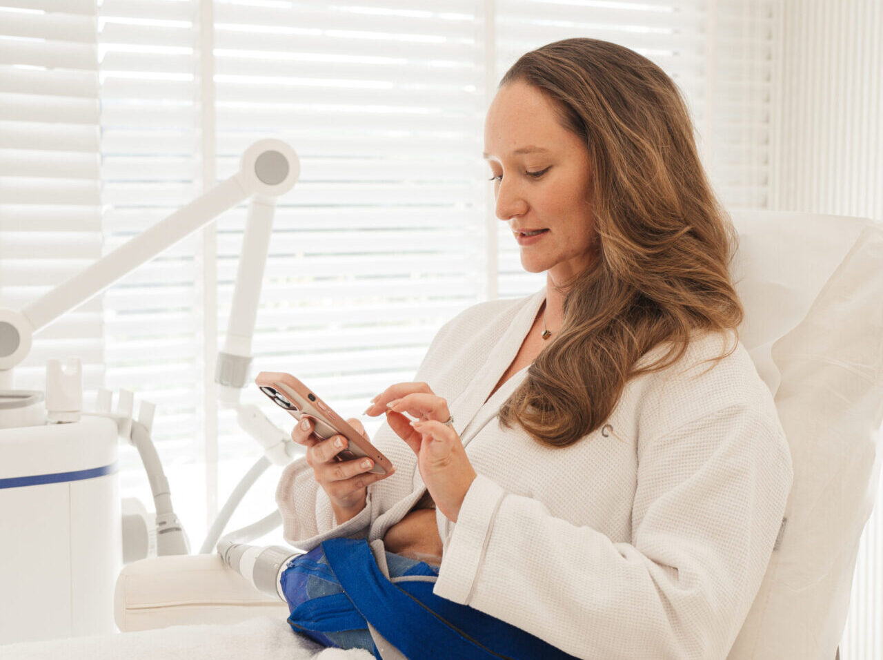 A woman looking at her phone to find questions to ask before an aesthetic procedure
