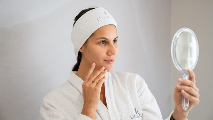 A woman looking at her face after a natural facelift