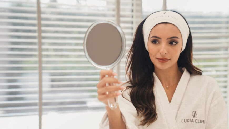A woman looking at a mirror, satisfied after aesthetic treatments